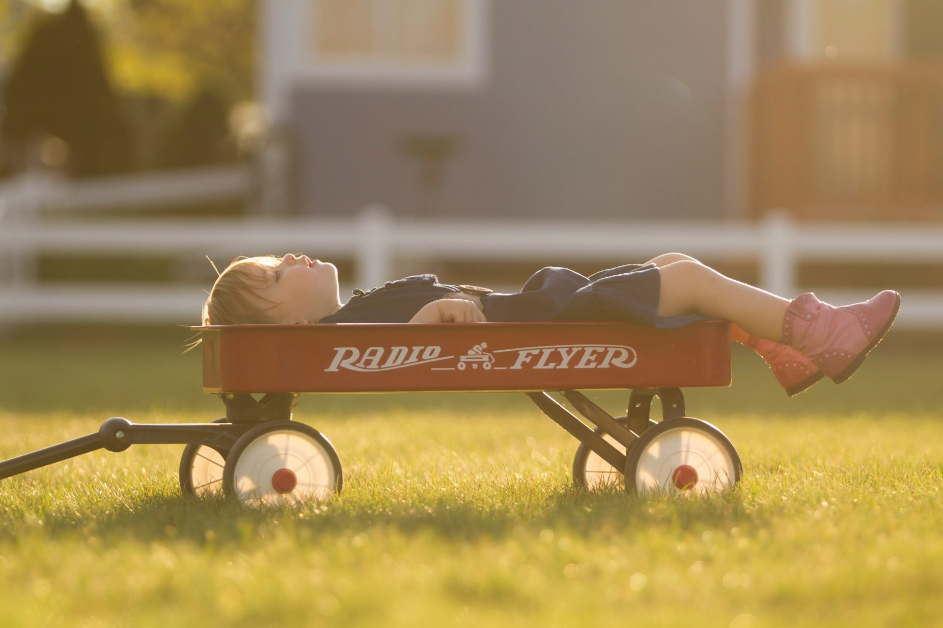 boy on red Radio Flyer pull wagon during daytime